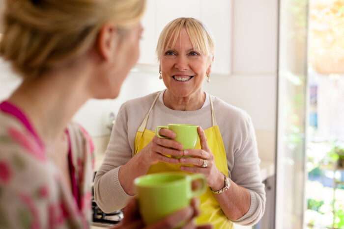 Mom and Older Daughter Drinking Coffee Together in Kitchen