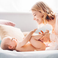 Mom Diapering Baby on Bed