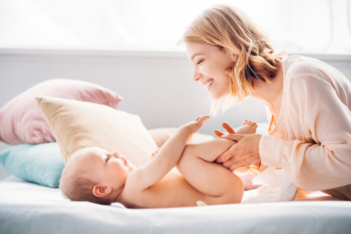 Mom Diapering Baby on Bed