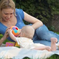 Mommy and baby playing on blanket outside on blanket