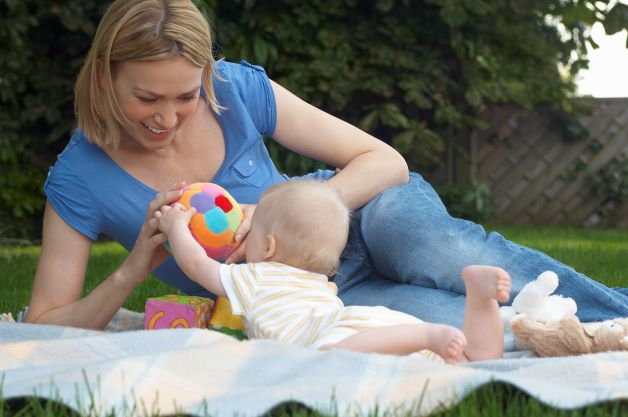 Mommy and baby playing on blanket outside on blanket