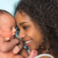 Mom holding newborn baby and smiling