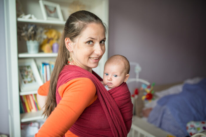 Close up of petite mom with baby in baby carrier