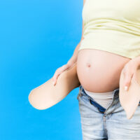 Pregnant woman putting on girdle
