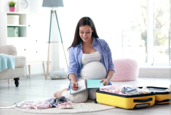 Pregnant woman packing hospital bag with checklist