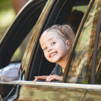 Cute little preschool girl looks out car window