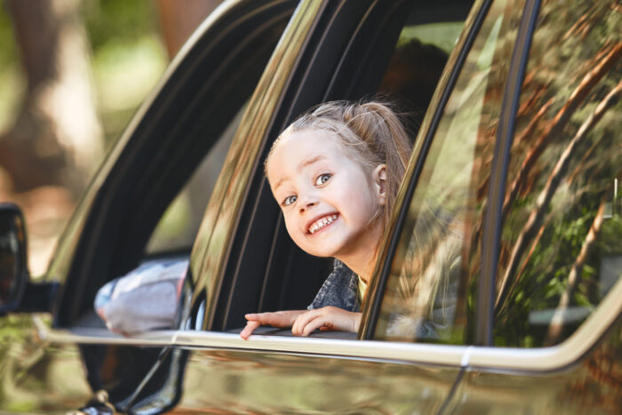 Cute little preschool girl looks out car window