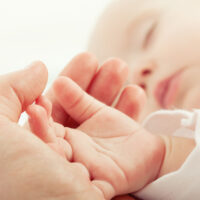 Sleeping baby's hand in Mama's hand