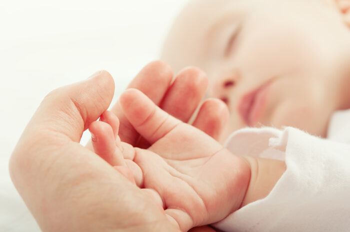 Sleeping baby's hand in Mama's hand