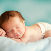 Sleeping baby with green background on green pillow