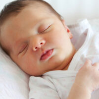 sleeping dark haired baby in infant swing