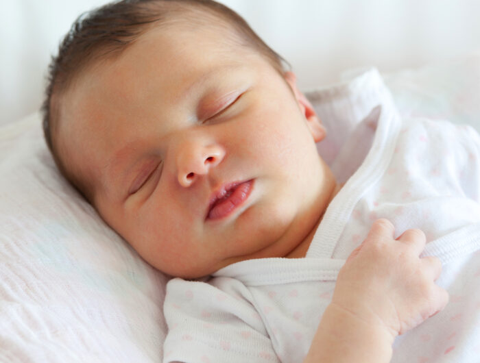 sleeping dark haired baby in infant swing