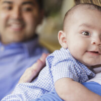 smiling father talking to mother while she burps their cute infant son