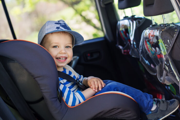 Smiling boy in baseball cap in car seat