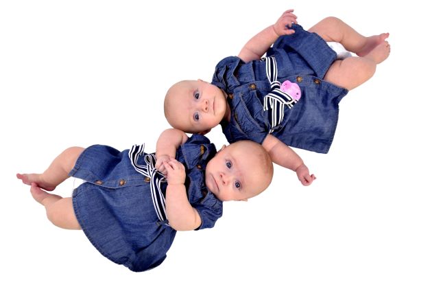 Twin baby girls laying together in denim dresses