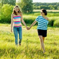Mom walking with teen daughter in green field
