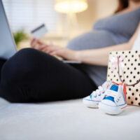 pregnant woman sitting on couch with laptop