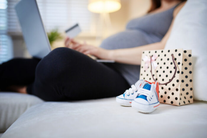 pregnant woman sitting on couch with laptop