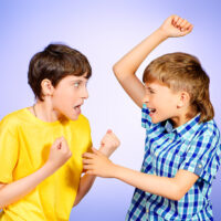 studio shot of two boys quarreling and trying to hit one another