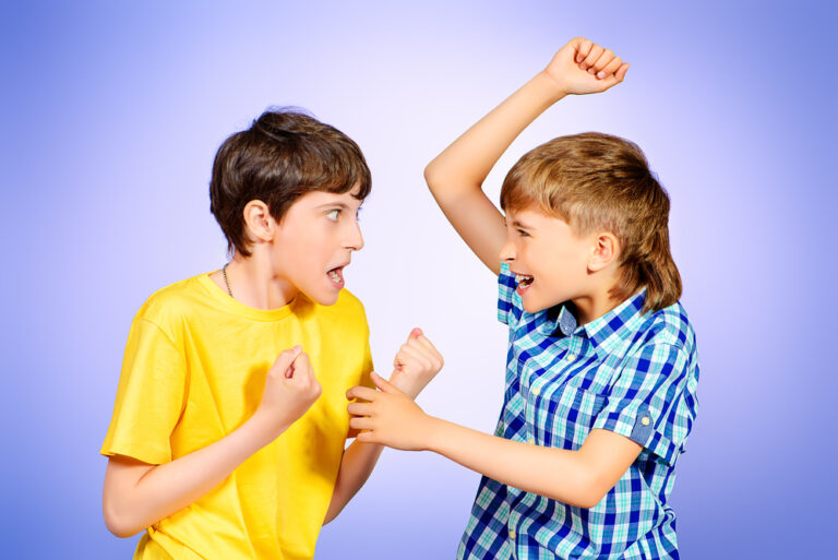 studio shot of two boys quarreling and trying to hit one another