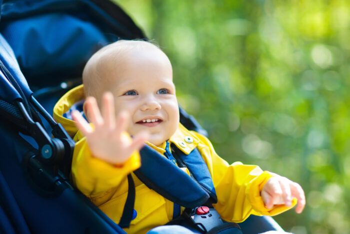 baby boy sitting in stroller during walk through park