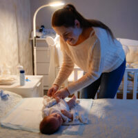 mother changing her baby's diaper at night