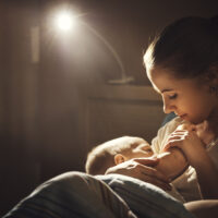 a mother breastfeeding her baby at night with light on