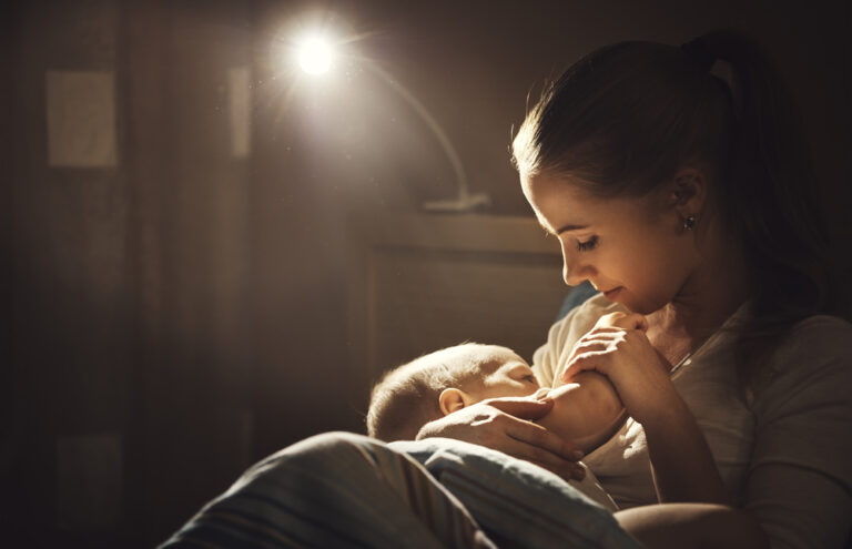 a mother breastfeeding her baby at night with light on