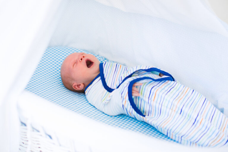 Little swaddled baby in white bed