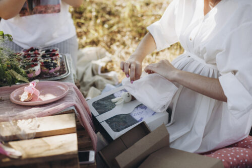 pregnant woman opening baby shower gift at park