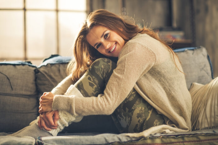 Smiling woman relaxing in leggings on sofa